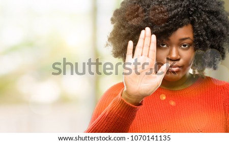 Beautiful african woman annoyed with bad attitude making stop sign with hand, saying no, expressing security, defense or restriction, maybe pushing, outdoor Royalty-Free Stock Photo #1070141135