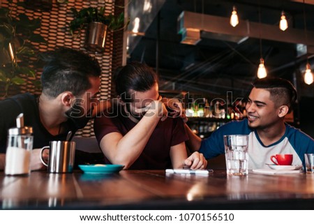 Happy arabian young men hanging in loft cafe. Group of mixed race people having fun in lounge bar