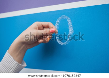 Hand hold invisible aligners plastic braces dentistry retainers to straighten teeth. blue background