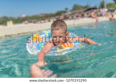 Little boy with colorful inflatable ring in sea