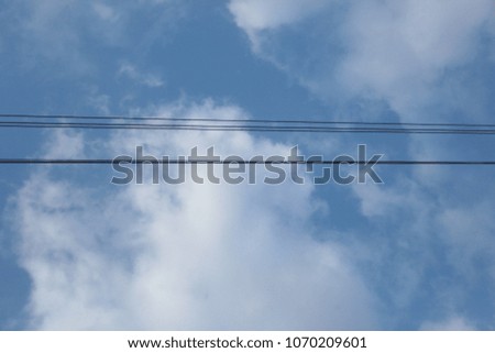 wide angle photography of a bright blue sky with white clouds, with black lined electric wires, on a sunny day outdoors in Poland, Europe
