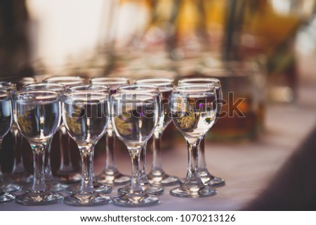Beautiful row line of different colored alcohol cocktails on a party, martini, vodka, tequila and others on decorated catering bouquet table on open air event, picture with beautiful bokeh