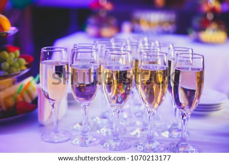 Beautiful row line of different colored alcohol cocktails on a party, martini, vodka, tequila and others on decorated catering bouquet table on open air event, picture with beautiful bokeh