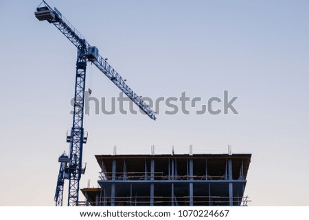 Silhouettes of tower cranes against the evening sky. House under construction. Industrial skyline