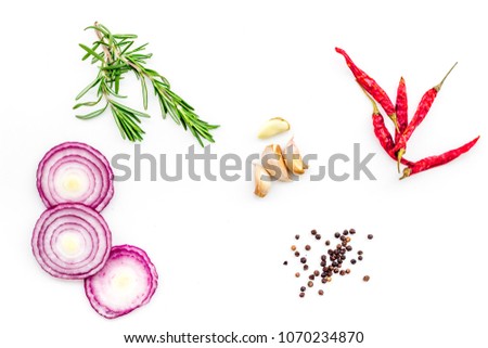 Red onion rings as seasoning. Onion near chili peper, rosemary, black peper, garlic on white background top view Royalty-Free Stock Photo #1070234870