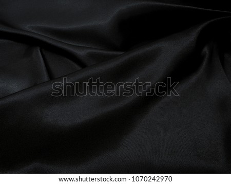 Black fabric texture background, wavy fabric slippery black color, luxury satin cloth texture for luxurious background or wallpaper.