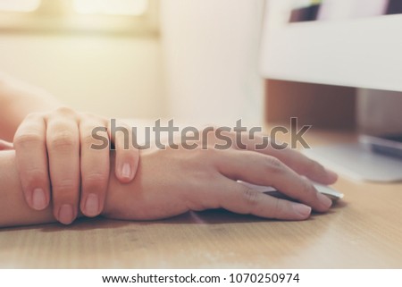 Hand of a businessman with a wrist injury of his own working a computer. Office syndrome concept