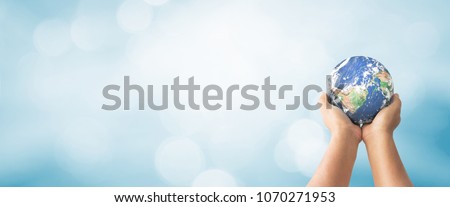 Earth Day concept: Human hands holding global over blurred blue nature background. Elements of this image furnished by NASA Royalty-Free Stock Photo #1070271953