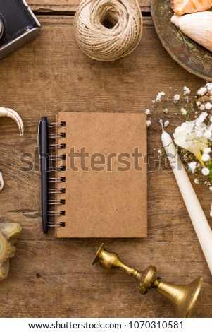 Spring or summer freelance and writing concept. Notepad with seashells, vintage film camera, gypsophila flowers, candle and vintage candleholders.