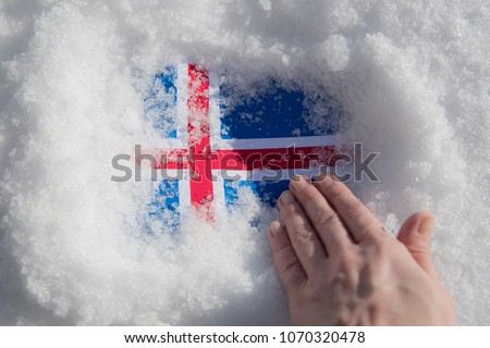 Texture of the Iceland flag in the snow and the hand that cleans it of snow.