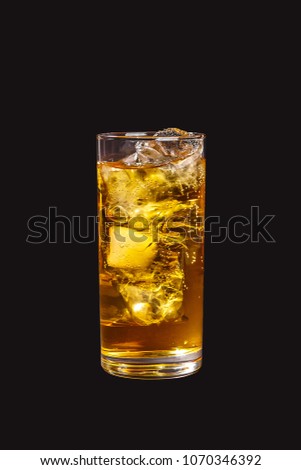 Single-color transparent cocktail, yellow refreshing carbonated in a high glass with ice cubes with apple, lemon, pear taste. Side view. Isolated black background. Drink for the menu Royalty-Free Stock Photo #1070346392