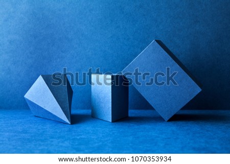 Geometrical figures still life composition. Three-dimensional prism pyramid tetrahedron rectangular cube objects on blue background. Platonic solids figures, simplicity concept photography