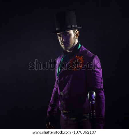 A mysterious man in a suit, with a cane, in a cylinder. Dark background. Scary and sinister. Joker, Halloween costume