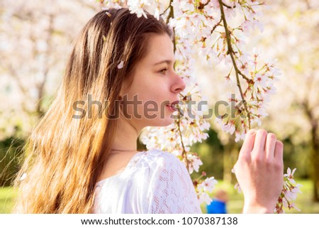 Spring portrait of a young teen girl in a cherry blossoming garden. A lovely girl and cherry flowers, a blooming spring.