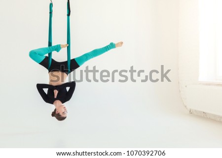 Happy woman practicing fly yoga asana over white background in fitness studio, copy space. Health, sport, yoga concept