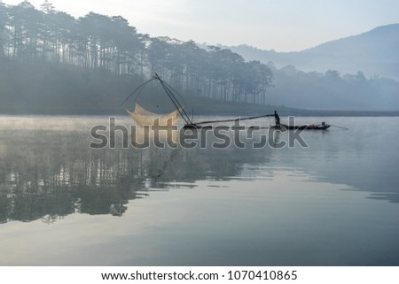 THE FISHER MAN ON HIS BOAT AT TUYENLAM LAKE IN DALAT CITY- VIETNAM