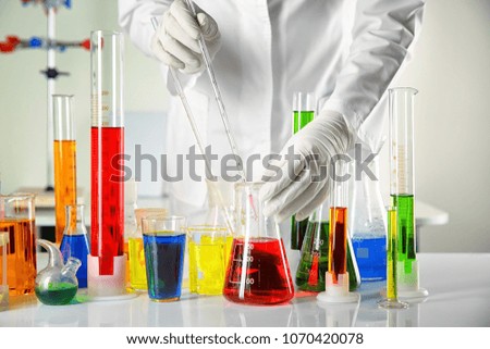 Scientist working with laboratory glassware at table