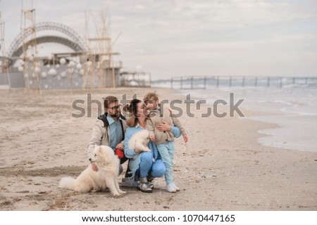 The family walks on a beach with a dog.