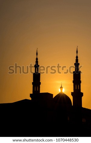 Silhouette of mosque and minarets on a sunset with the sun behind.