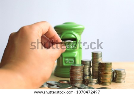 Close-up of a hand holding a coin in a green piggy bank selective focus and shallow depth of field