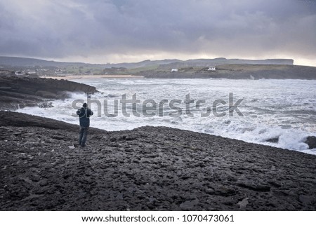 A person takes pictures of the sea during the storm with his mobile
