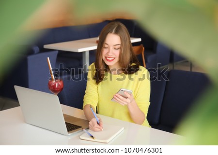 Young freelancer working with laptop and mobile phone in cafe