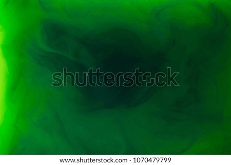 full frame image of mixing of green and black paints splashes in water isolated on gray