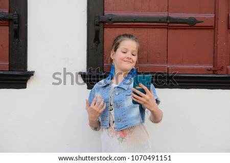 Pretty scool age girl making selfie by smartphone in the old town
