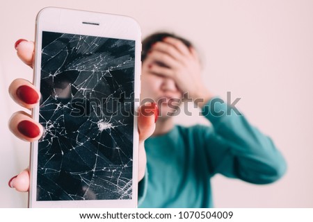 Broken glass screen smartphone in hand of upset girl, white background.