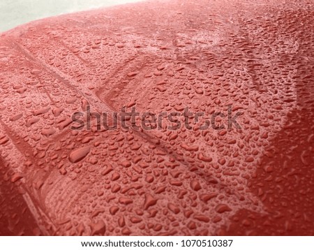 Raindrop or droplet on the orange car surface.