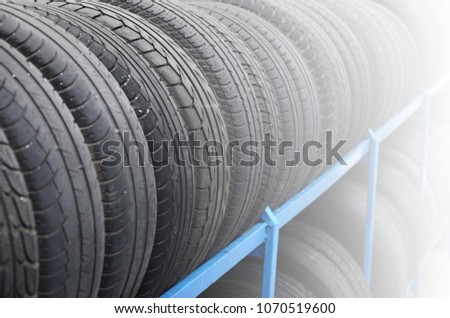 Rack with variety of car tires in automobile store. Many black tires. Tire stack background. Selective focus