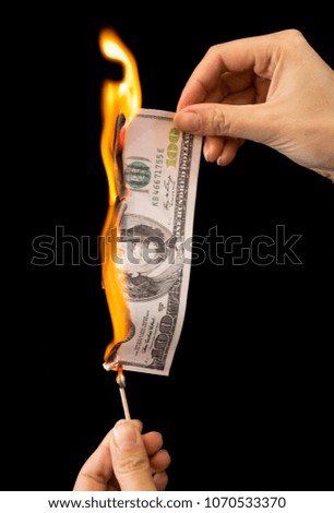 One hundred dollars burn in the hand on a black background
