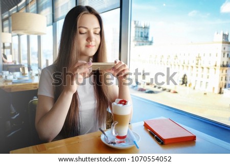 beautiful girl is making photo of food in cafe, latte on the table, communication in social networks