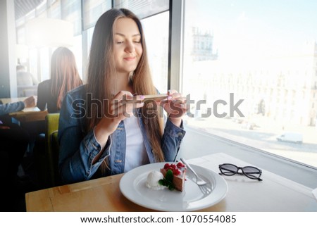 beautiful emotional happy girl is making photo of food in cafe, latte on the table, dessert ice cream chocolate cake cherry mint, communication in social networks