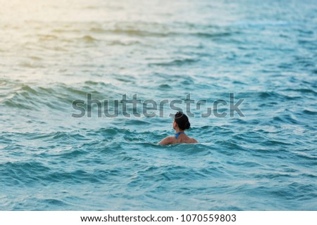 woman in the morning swims in the sea or the ocean and watches the dawn, concept life style, relaxation, early morning