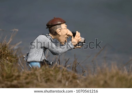 A funny clay figurine of a photographer with an ancient camera shot on a blurred homogeneous background