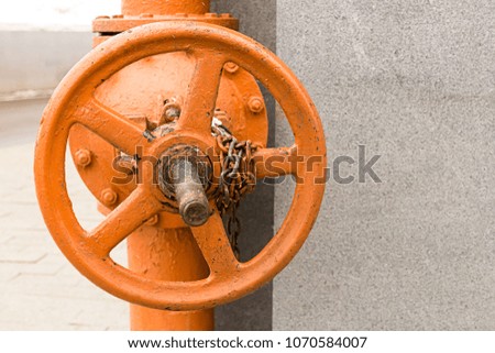 industrial background orange big faucet on long gates with chain background of gray stone wall copy space