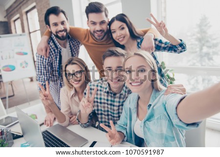 Self portrait of attractive, stylish economists shooting selfie on front camera with joyful cheerful expression having leisure, timeout, break, pause, rest, relax, hugging, showing two fingers Royalty-Free Stock Photo #1070591987