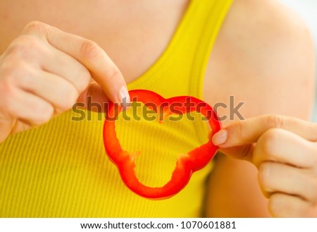 Closeup on woman holding slice of bell pepper near heart