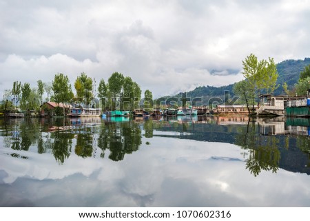 Reflection of houseboat at Dal Lake, Srinagar, Kashmir, India during sunrise. Sightseeing with shikara ride, a traditonal boat at Dal Lake. Image may contains a bit noise due to low light environment