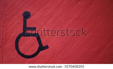 Black wheelchair sign on red grunge concrete wall