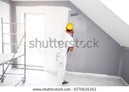 Room painter paints a wall in a new home. Unrecognizable Person.