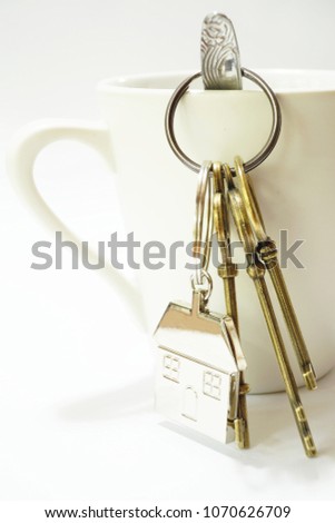 House metal keys with steel keyring hanging on with coffee cup and white background
