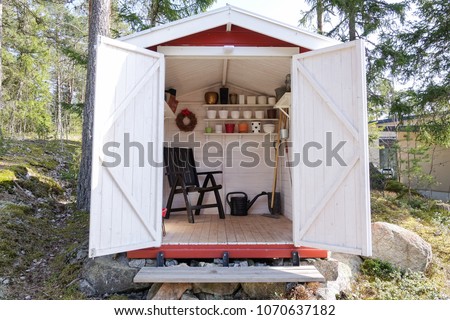 Storage shed filled with garden tools. Shovels, rake, pots, water pitcher and all you need for gardening.