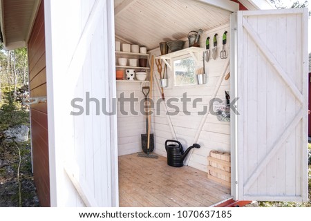 Storage shed filled with garden tools. Shovels, rake, pots, water pitcher and all you need for gardening.