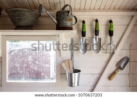 Garden tools in a small storage shed. Shovels, rake, water pitcher and all you need for gardening.
