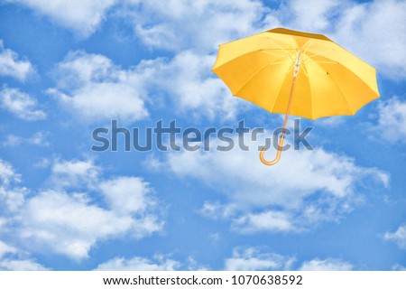 Mary Poppins Umbrella.Yellow umbrella flies in sky against of white clouds.Wind of change concept. Royalty-Free Stock Photo #1070638592