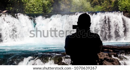 Silhouette of a person making a video of the cascade Salto de la Leona. Huilo-Huilo park, Chilean Andes.