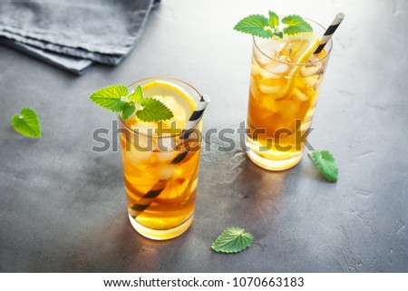 Iced Tea with lemon, mint and ice cubes over gray concrete background, copy space. Iced cold summer drink.