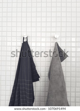two towels are hanged on small square ceramic wall